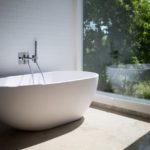 Eine freistehende Badewanne im Badezimmer mit einem Ausblick ins Grüne