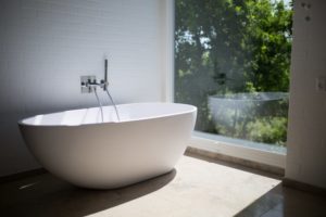 Eine freistehende Badewanne im Badezimmer mit einem Ausblick ins Grüne