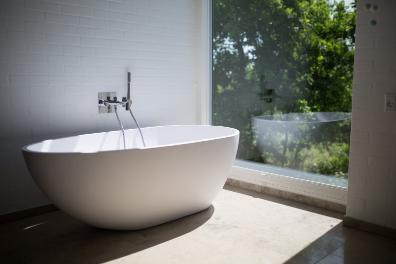 Eine freistehende Badewanne im Badezimmer mit einem Ausblick ins Grüne