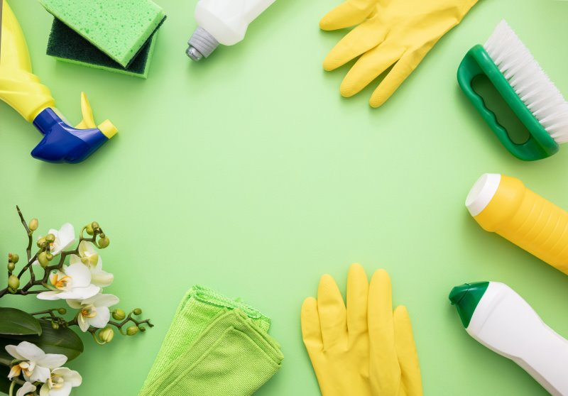 Mehrere Putzutensilien, darunter Essigreiniger, Gummihandschuhe, Reinigungsprodukte und Lappen