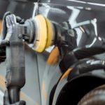 Eine Poliermaschine wird an einem schwarzen Auto zur professionellen Aufbereitung genutzt