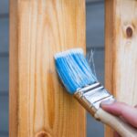 Holzschutzlasur wird auf Zaun aufgetragen
