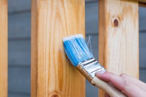 Holzschutzlasur wird auf Zaun aufgetragen