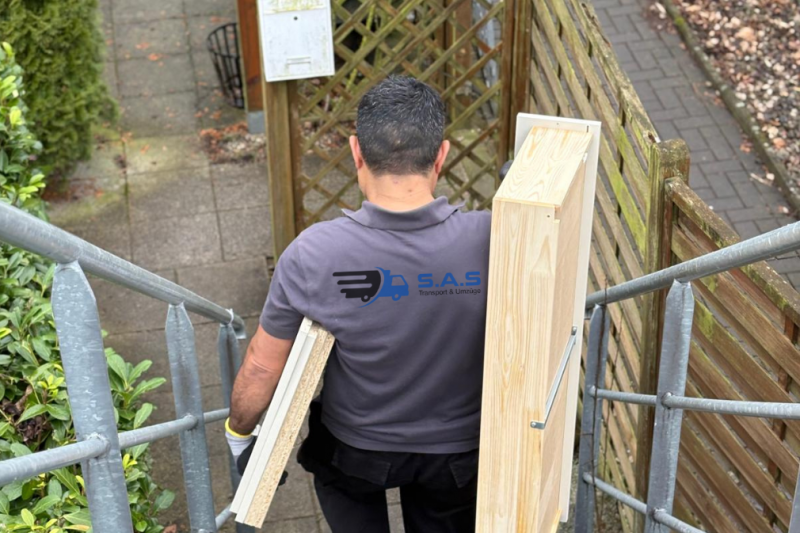 Möbeltransport durch Umzugshelfer mit Holzteilen auf einer Treppe
